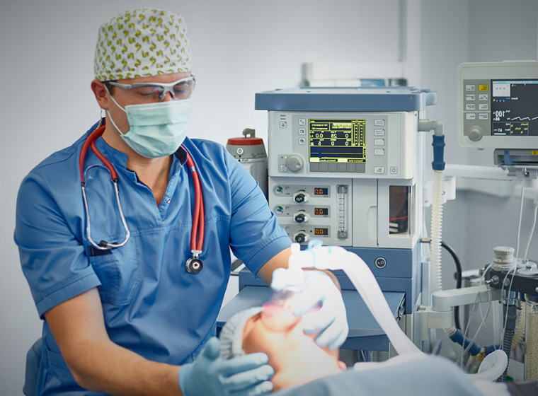 A man holds an anaesthetic mask to a patient's face